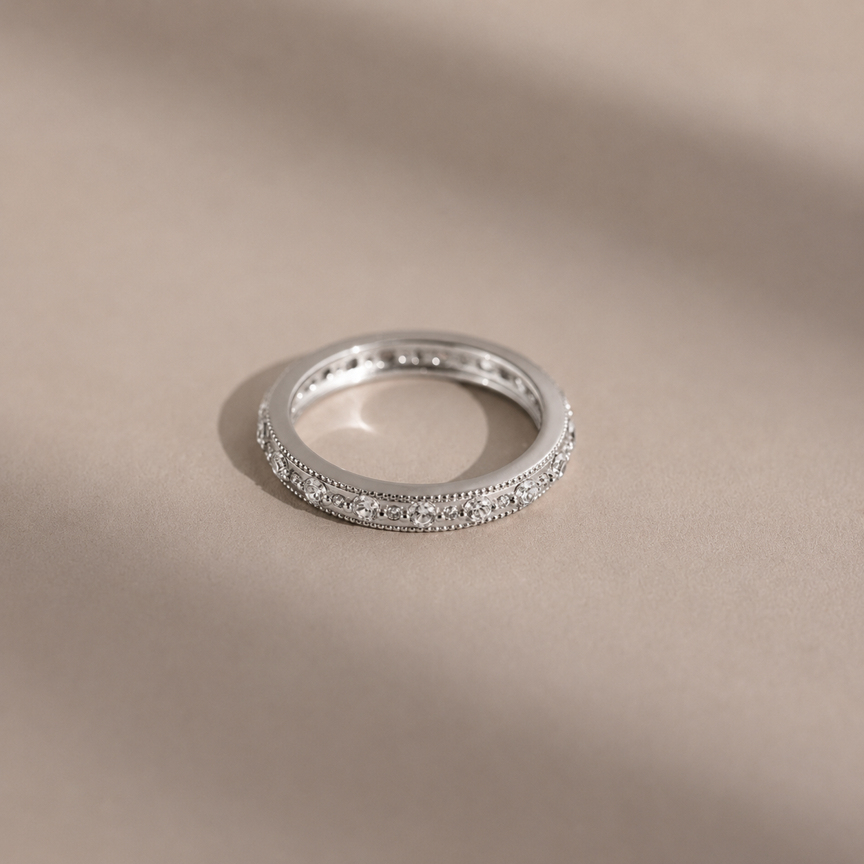 Silver ring with small diamonds on a beige background